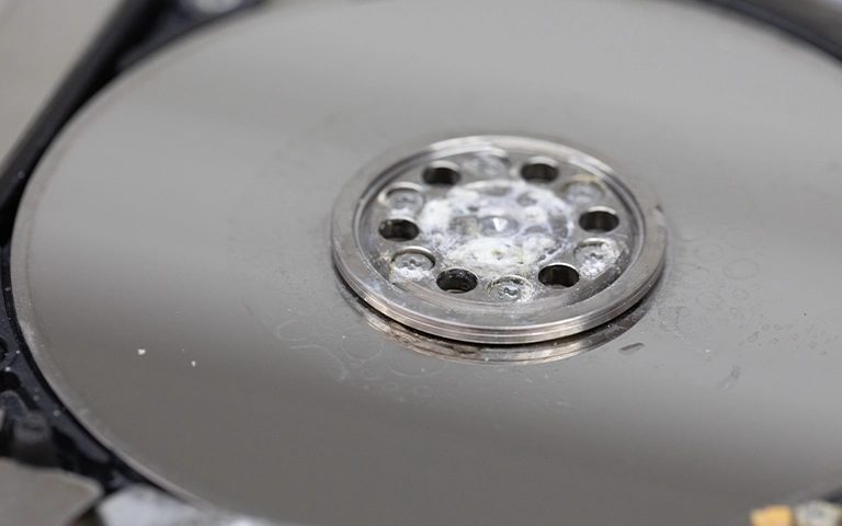 Hard disk plakasının merkezinde ve yüzeyinde kurumuş sıvı kalıntıları ve beyaz tortular