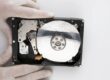 Eldivenli ellerde kapağı açılmış, plakasında su lekeleri bulunan ıslanmış hard disk