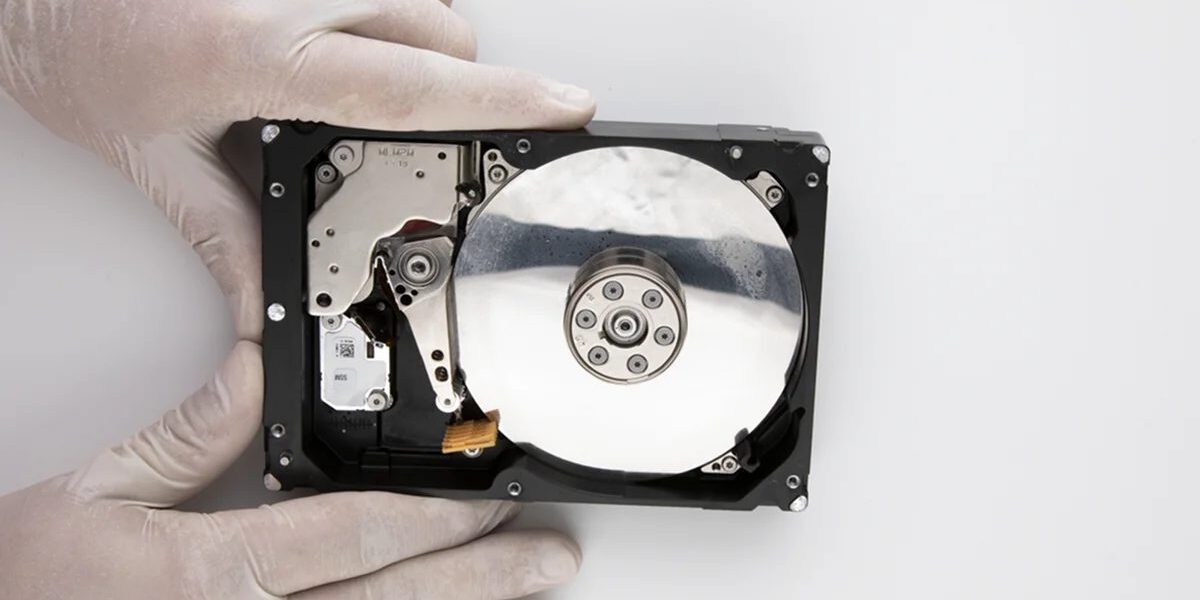 islanan-hard-disk-veri-kurtarma-xwvx8l Eldivenli ellerde kapağı açılmış, plakasında su lekeleri bulunan ıslanmış hard disk