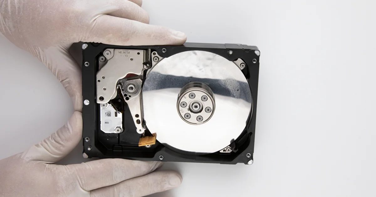 Eldivenli ellerde kapağı açılmış, plakasında su lekeleri bulunan ıslanmış hard disk