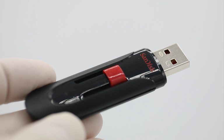 Eldivenli elde tutulan siyah-kırmızı SanDisk USB bellek