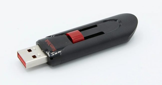 Beyaz zemin üzerinde siyah-kırmızı sürgülü SanDisk USB bellek